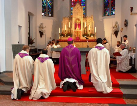 Die Geistlichen knien vor dem Altar